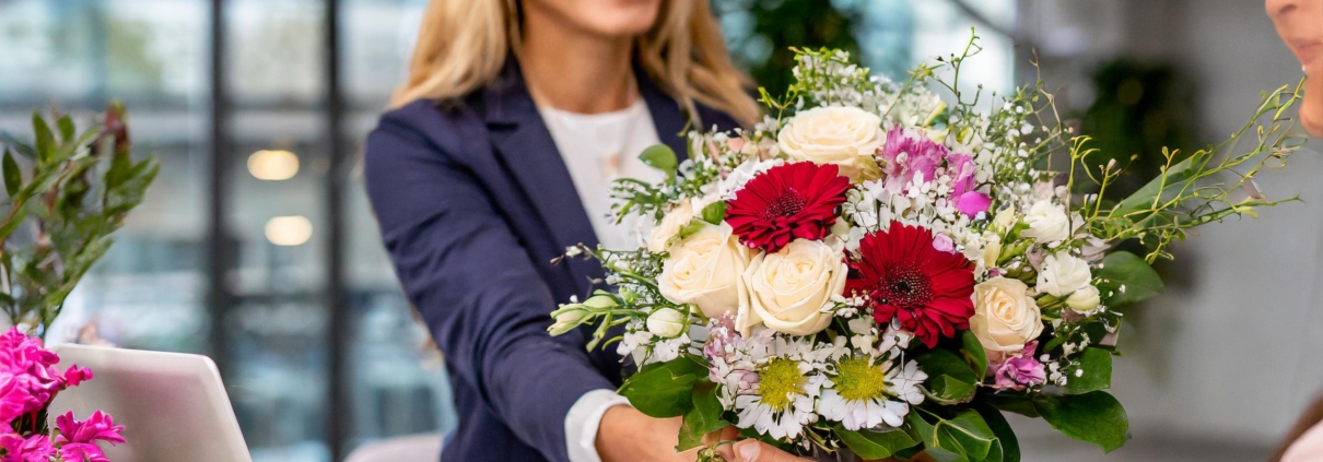 Verschiedene frische Blumensträuße auf einem Bürotisch als Zeichen der Anerkennung für Mitarbeiter