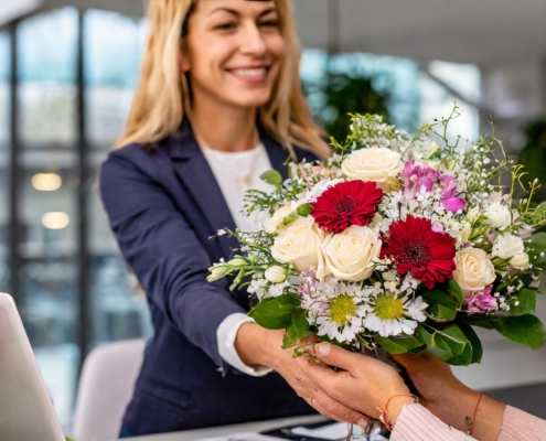 Verschiedene frische Blumensträuße auf einem Bürotisch als Zeichen der Anerkennung für Mitarbeiter